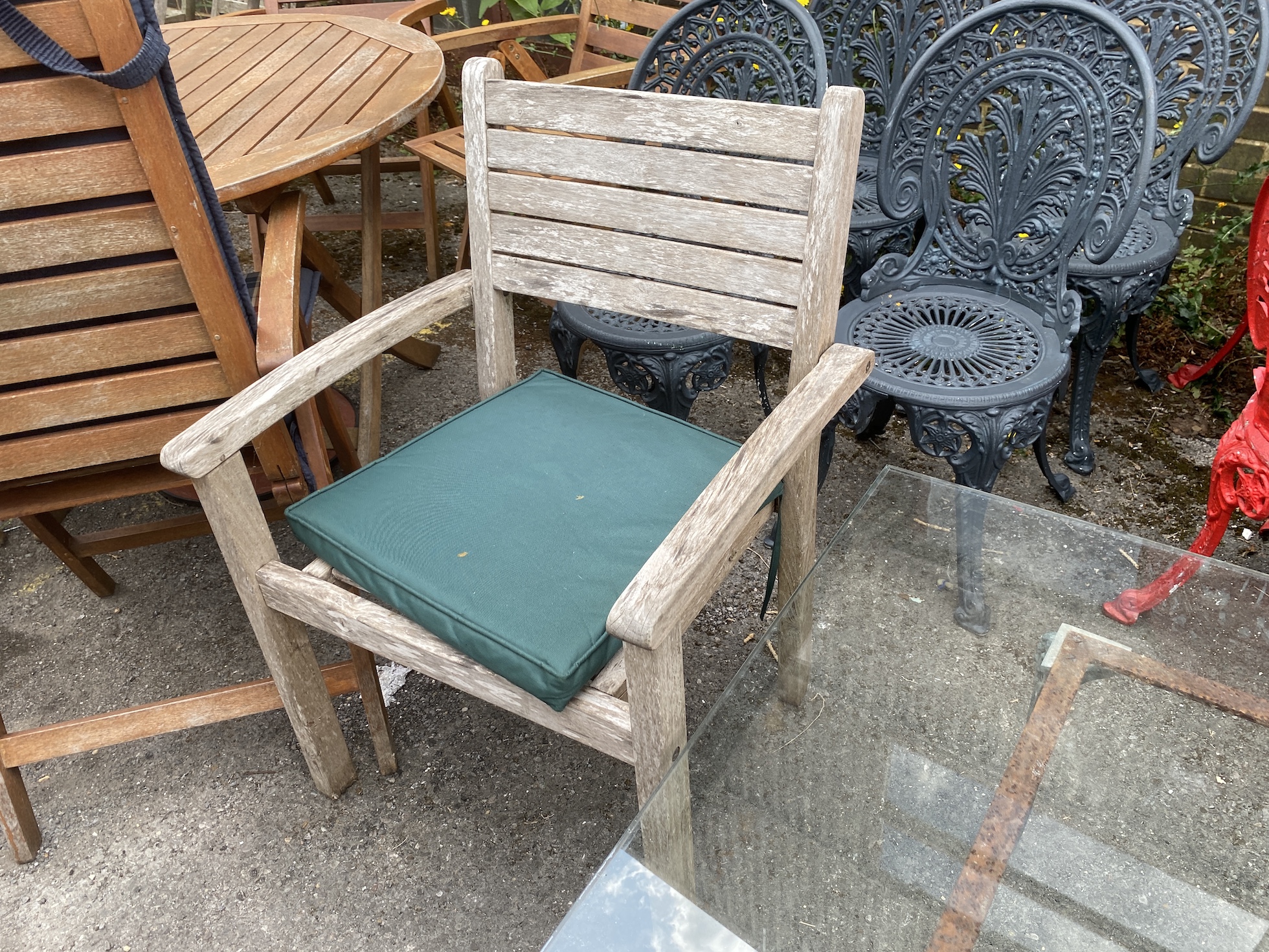 A square glass top cast metal garden table on a metal base, length 100cm, height 44cm together with a pair of teak elbow chairs